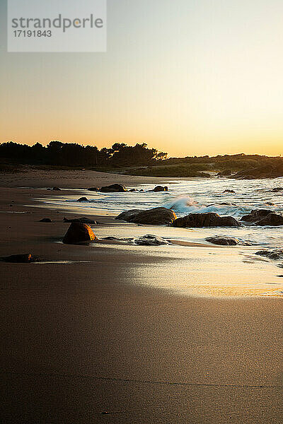 Sonnenuntergang an einem Strand mit Felsformationen an der galicischen Küste