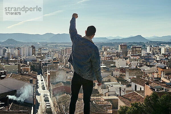 Ein Mann erhebt seine Faust auf einem Dach mit Blick auf die Stadt