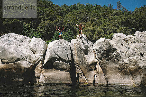 Zwei Jungen springen von Felsblöcken am Yuba River