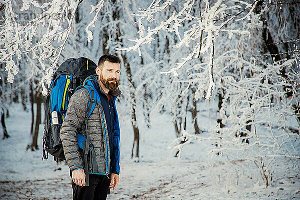 gutaussehender Mann beim Trekking in schöner Winterlandschaft soziale Dista