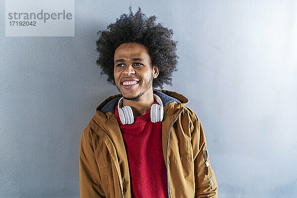 Porträt eines jungen Mannes mit Afro-Haar über einer grauen Wand