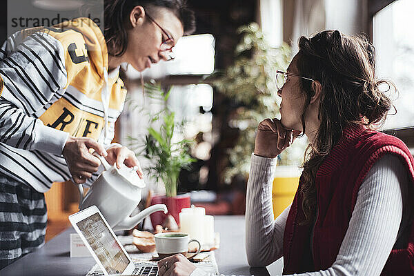 Berufstätige Frauen trinken Tee und treffen sich während des Einschlusses zu Hause mit ihrem Laptop