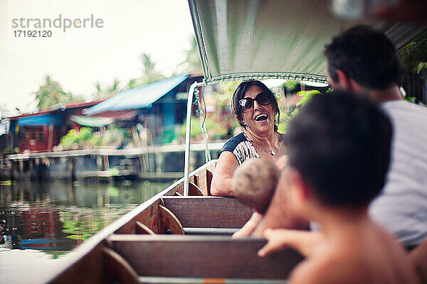 Lachende Frau auf einem Boot auf einem schwimmenden Markt in Bangkok Thailand.