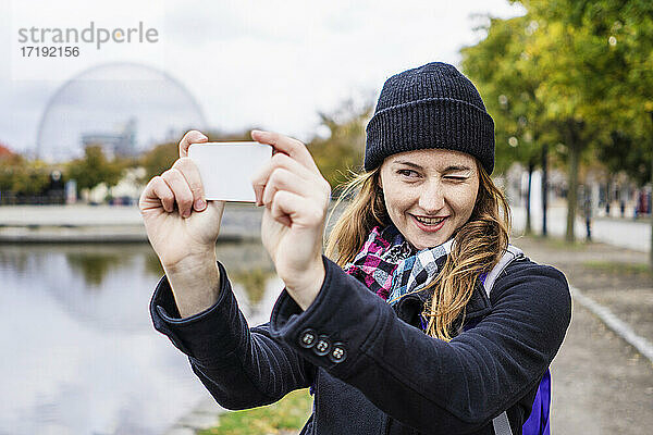 Alleinreisende Frau beim Fotografieren mit Smartphone