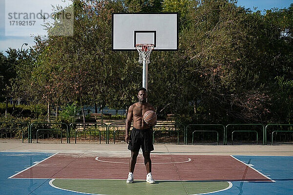 Schwarzer Mann ohne Hemd in der Nähe des Basketballkorbs