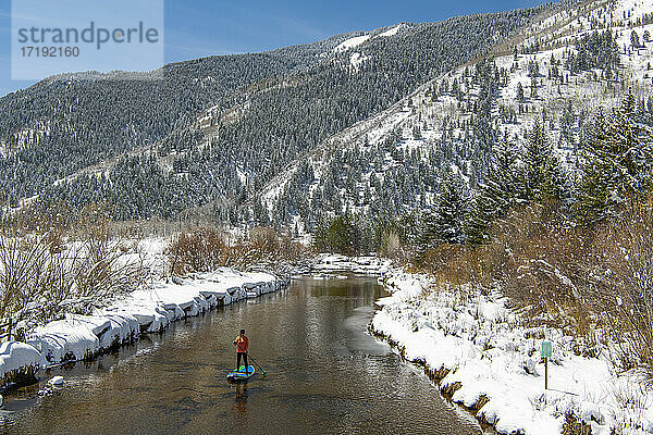 Frau paddelt im Winter auf einem Fluss