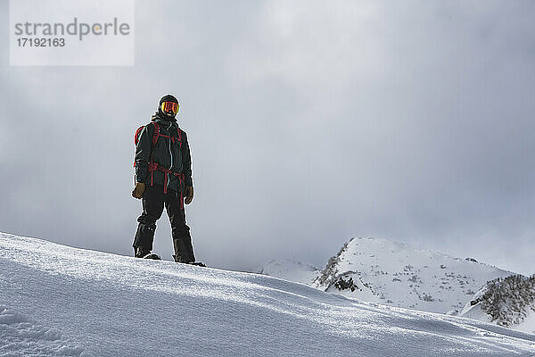Lächelnder Mann beim Snowboarden auf einem schneebedeckten Berg