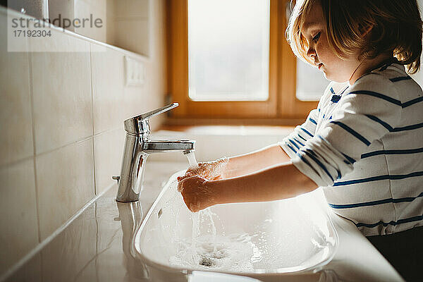 Seitenansicht eines jungen Kindes im Vorschulalter  das sich die Hände mit Seife wäscht