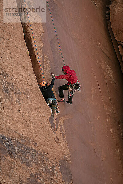 Männer  die sich beim Klettern an einer Klippe im Canyonlands National Park zuprosten