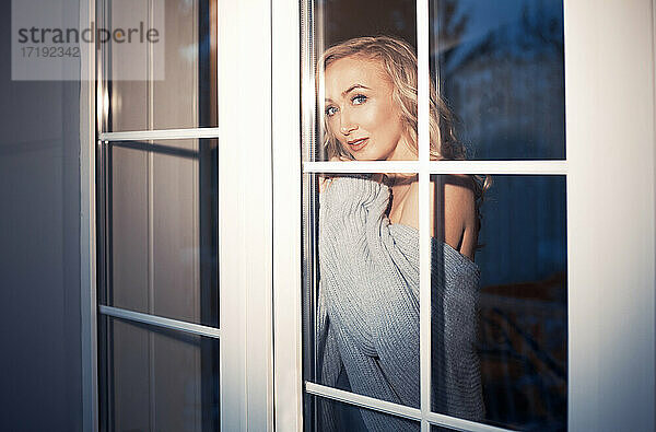 Blonde Frau hinter dem Fenster