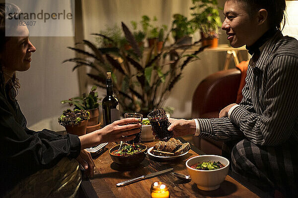 zwei Frauen  die sich zu Hause über ein gesundes Abendessen freuen und lächeln