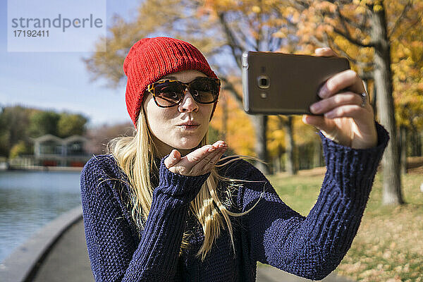 Kanadische Frau macht im Park ein Selfie mit ihrem Smartphone