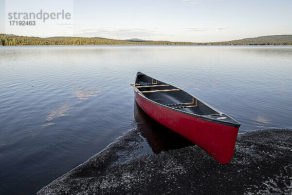 Rotes Kanu am felsigen Ufer des unberührten Bald Mountain Pond  Maine