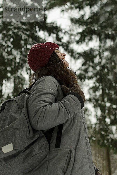 Ein Mädchen mit rotem Hut  schaut in den Himmel  lächelt  es schneit  reist.