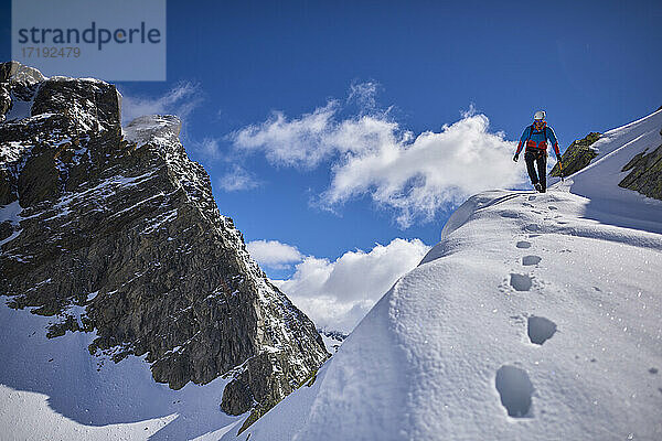 Ein Mann besteigt an einem sonnigen Tag einen verschneiten Berg in Devero  Italien.