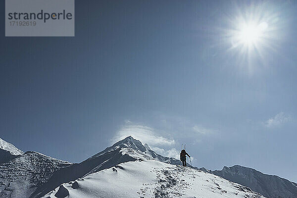 Low angle view of man splitboarding against sky during sunny day