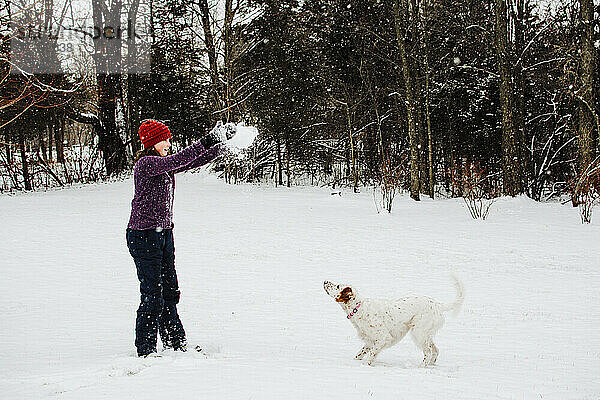 Mädchen spielt im Schnee mit ihrem Hund in Süd-Michigan