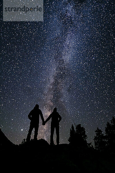 Silhouette Paar hält die Hände  während gegen schöne Sterne Feld in der Nacht stehen