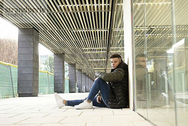 Junger Mann sitzt auf dem Boden im Freien und entspannt sich