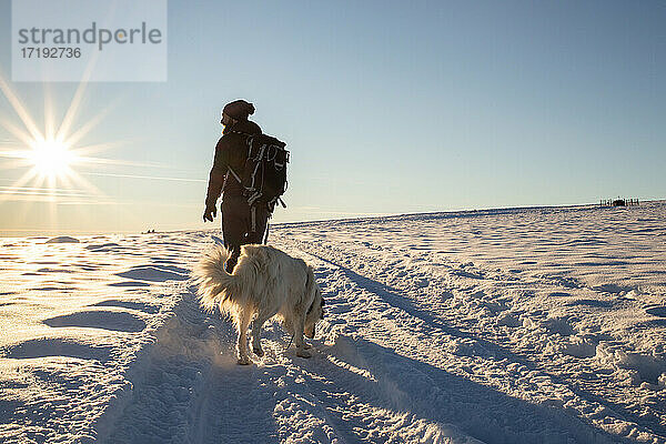 Mann mit Hund beim Trekking im Winterschnee