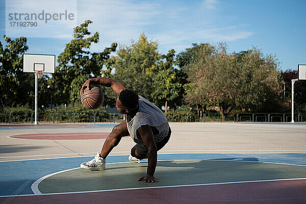 Muskulöser afroamerikanischer Spieler beim Freestyle-Dribbling auf dem Platz