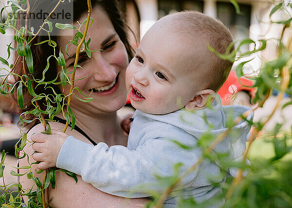 Mutter und kleiner Sohn lachend im Vorgarten bei der Trauerweide