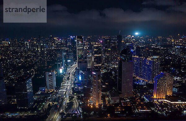 Modernes Stadtzentrum mit Wolkenkratzern bei Nacht Stadtbeleuchtung und Straßenverkehr in Jakarta  Indonesien  bei Dunkelheit