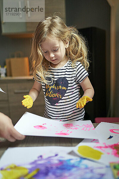 Nettes kleines Mädchen Künstler mit gemalten Palmen erforscht ihre Kunstwerk auf weißem Blatt Papier.