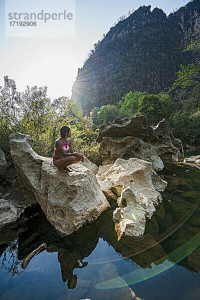 Junge Frau entspannt sich am Fluss Tha Falang in Laos