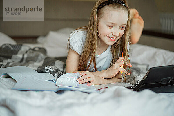 Mädchen auf dem Bett liegend  umgeben von Notizbüchern