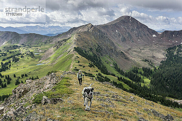 Wanderin mit Hund auf einem Berg gegen bewölkten Himmel