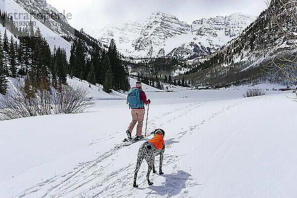 Junge Frau beim Wandern mit Pointer-Hund im Winter