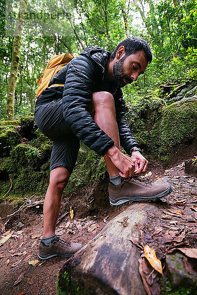 Junger Mann bindet sich beim Trekking die Schuhe