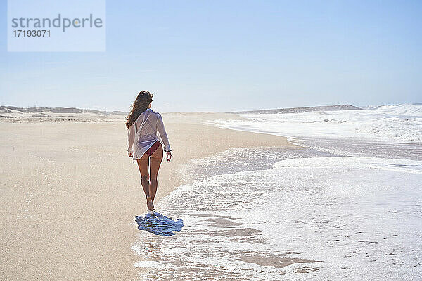 Mädchen von hinten  das an einem einsamen und paradiesischen Strand spazieren geht und die Freiheit genießt.