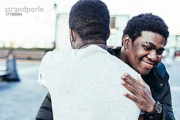 Porträt von zwei afroamerikanischen Freunden  die sich umarmen. Wiederbegegnung in einem städtischen Raum.