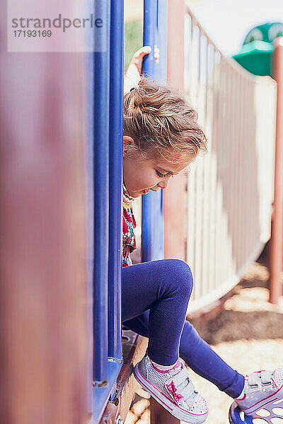 Kleines Mädchen spielt allein auf einem öffentlichen Spielplatz.