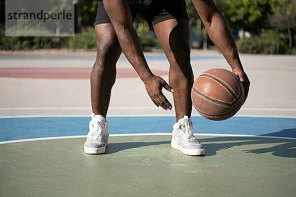 Geschnittener schwarzer Sportler dribbelt Basketball