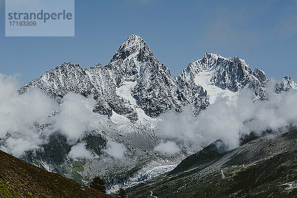 Massive Gipfel in den französischen Alpen umgeben von Wolken mit Gletschern darunter