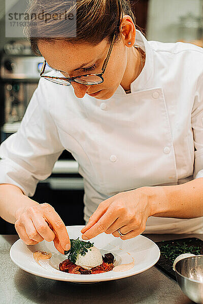 Michelin-Koch beim Dekorieren von Speisen auf dem Teller während der Arbeit im Restaurant