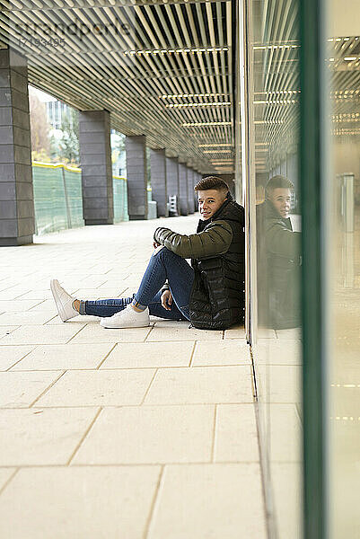 Junger Mann sitzt auf dem Boden im Freien und entspannt sich
