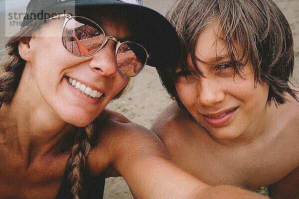 Mutter und Sohn posieren für ein Selfie am Strand