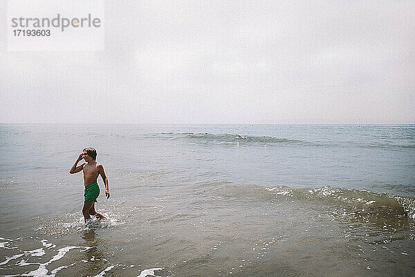 Junger Junge spielt in den Wellen an einem kalifornischen Strand