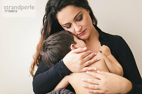 Eine Mutter  die ihren schlafenden Sohn an ihre Brust drückt.