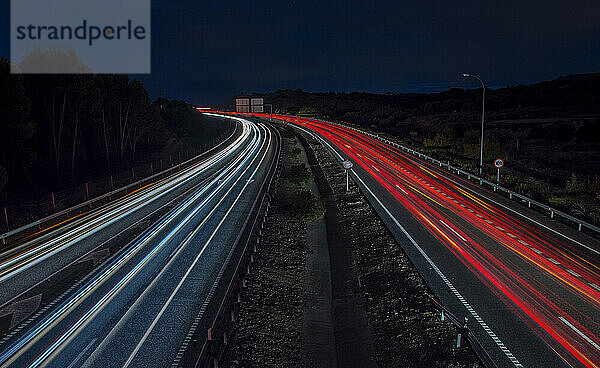 Autoampel auf der Autobahn in der Abenddämmerung. Langzeitbelichtungsaufnahme. Blaue  weiße und rote Lichter.