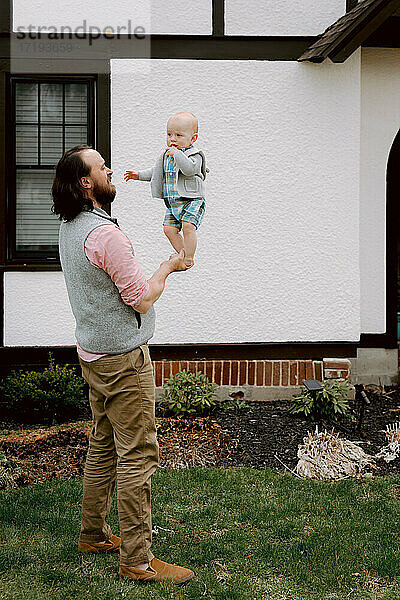 Spaß Vater spielt mit verwirrten Baby Sohn im Vorgarten im Frühjahr