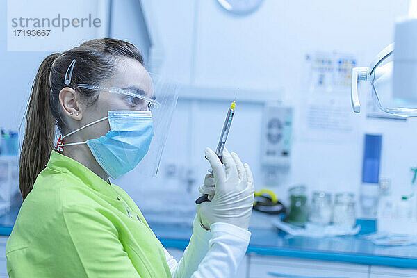 Zahnärztin bei der Vorbereitung der Anästhesiespritze mit Maske