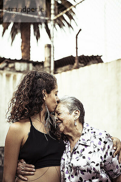 Junge attraktive Mexikanerin küsst ihre Großmutter auf der Sommerstraße