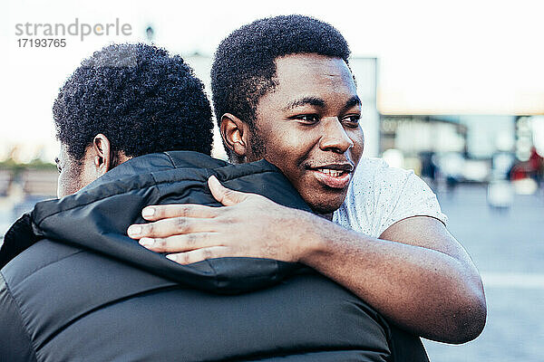 Porträt von zwei afroamerikanischen Freunden  die sich umarmen