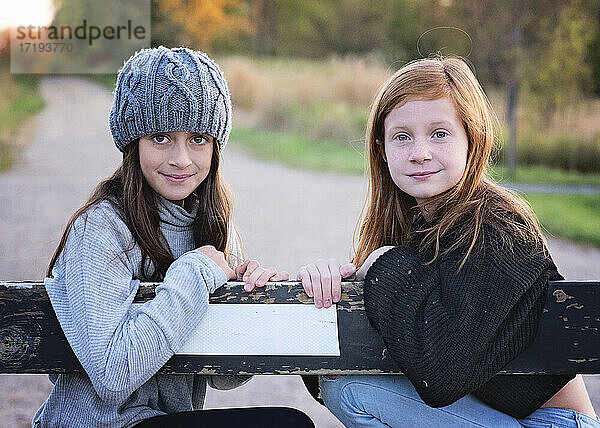 Zwei junge Mädchen in Pullovern im Freien auf einer Landstraße.