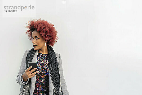 schöne Frau mit Afro-Haar sendet eine Nachricht von ihrem Smartphone